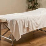 Table de massage professionnelle avec cadre aluminium et drap blanc dans un institut de bien-être moderne